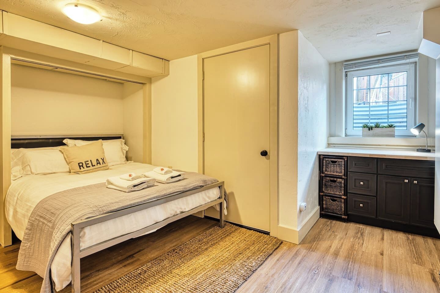 A bedroom with a bed, a bedside table, a window, and a built-in cabinet.
