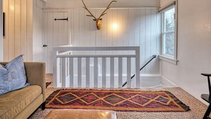 A room with a white railing, a patterned rug, a sofa, and a mounted animal head. - 5 Bedroom, 3 Bath House! With Brand New Hot Tub! (Eugene)