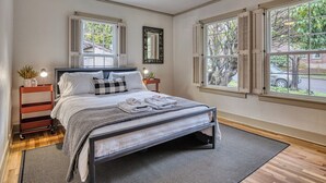 A bedroom with a bed, bedside tables, a ceiling fan, and windows with shutters. - 5 Bedroom, 3 Bath House! With Brand New Hot Tub! (Eugene)