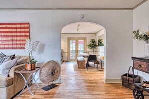 Un salon comprenant un canapé, une table basse, une sphère décorative en bois et un drapeau américain accroché au mur.