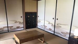A traditional Japanese room with tatami flooring, a wooden table, and shoji screens depicting a cloud landscape. - Uego (Niijima)