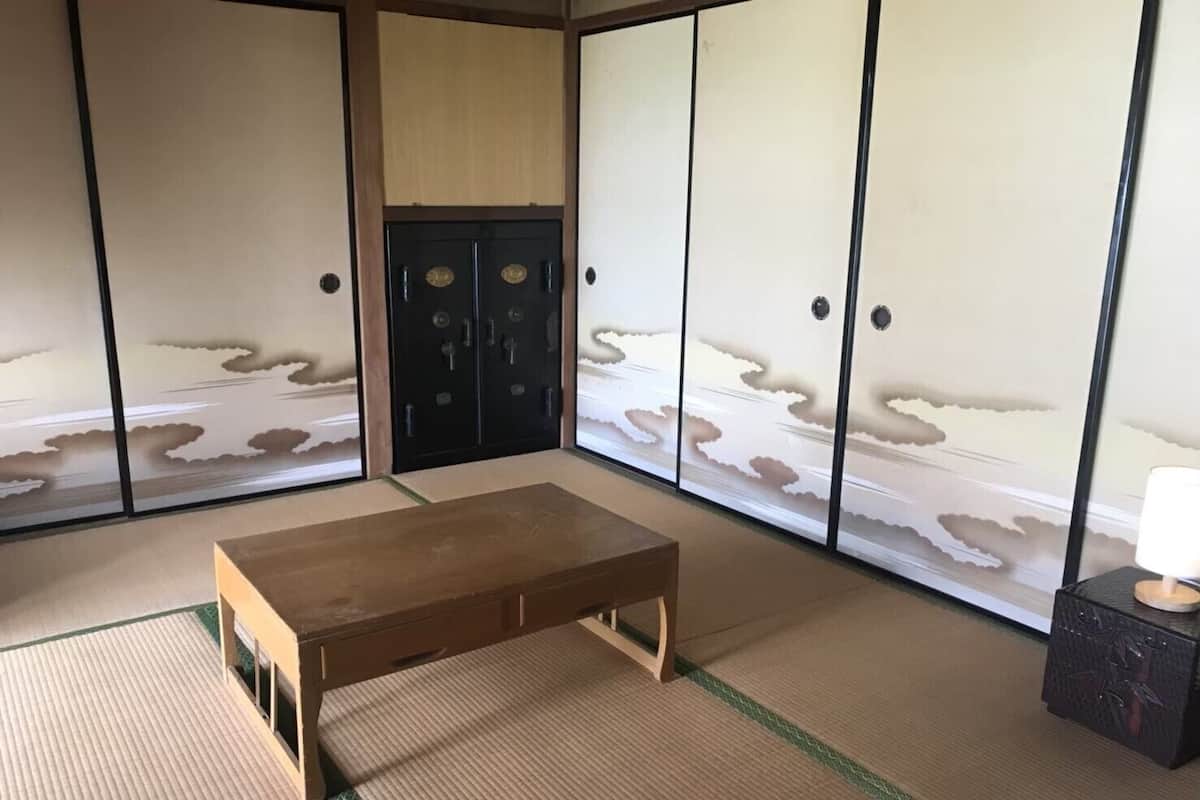 Ein traditioneller japanischer Raum mit Tatami-Bodenbelag, einem Holztisch und Shoji-Schirmwänden mit Landschaftsbildern von Wolken.