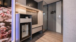 A modern hotel room with a built-in TV, a minibar, and a wardrobe. - Aspira Gems Center Silom (Bangkok)
