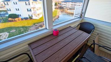 A room with a window overlooking a residential area, a wooden table, and two chairs.