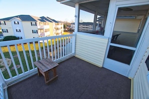 Een balkon met een houten bankje, een witte balustrade en uitzicht op omliggende gebouwen.