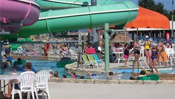 A water park with multiple slides and pools, surrounded by beach chairs and umbrellas.