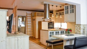 A compact kitchen with a central island, wooden cabinets, and pendant lighting.