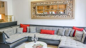 A modern living room with a sectional sofa, a white coffee table, and a decorative wall shelf.
