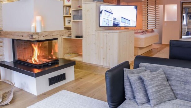 A cozy living room with a fireplace, wooden shelves, a television, and a sofa.