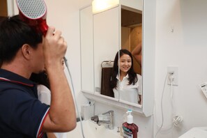A bathroom with a mirror, sink, and a hairdryer. - IBASHO Shibuya Sakura 4F (Tokyo)
