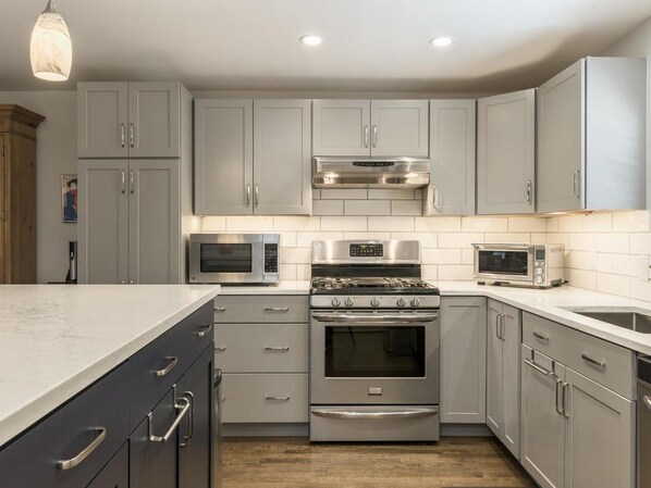 Enjoy cooking in this well-lit kitchen with a range hood, oven, microwave, and double sink.