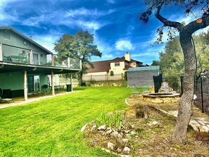 Enjoy the serene atmosphere of this backyard with lush greenery and a tree, surrounded by a secure metal fence.
