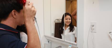 A bathroom with a mirror, sink, and a hairdryer.