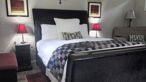 A neatly arranged bedroom with a large bed, two bedside lamps, a decorative wall piece, and a red patterned rug. - The BirdDog Farm Cabin #1        (Dixon Springs)