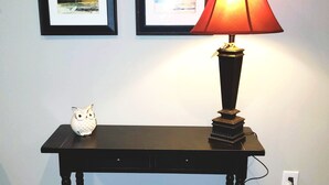 A black console table with a red lamp, two framed artworks, and a small owl figurine. - The BirdDog Farm Cabin #1        (Dixon Springs)