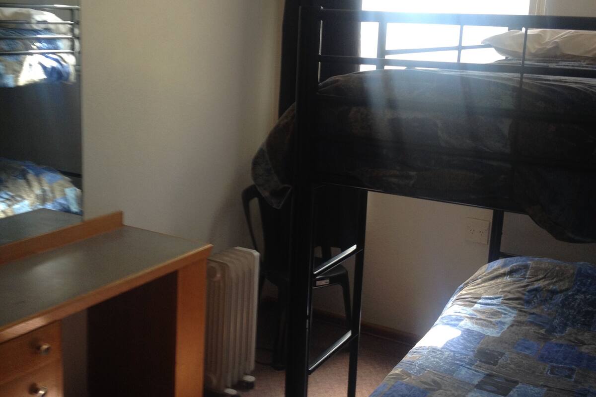 Un dormitorio con literas, un escritorio y un radiador.