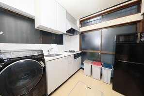A compact kitchen with a washing machine, a sink, a stove, and a refrigerator.