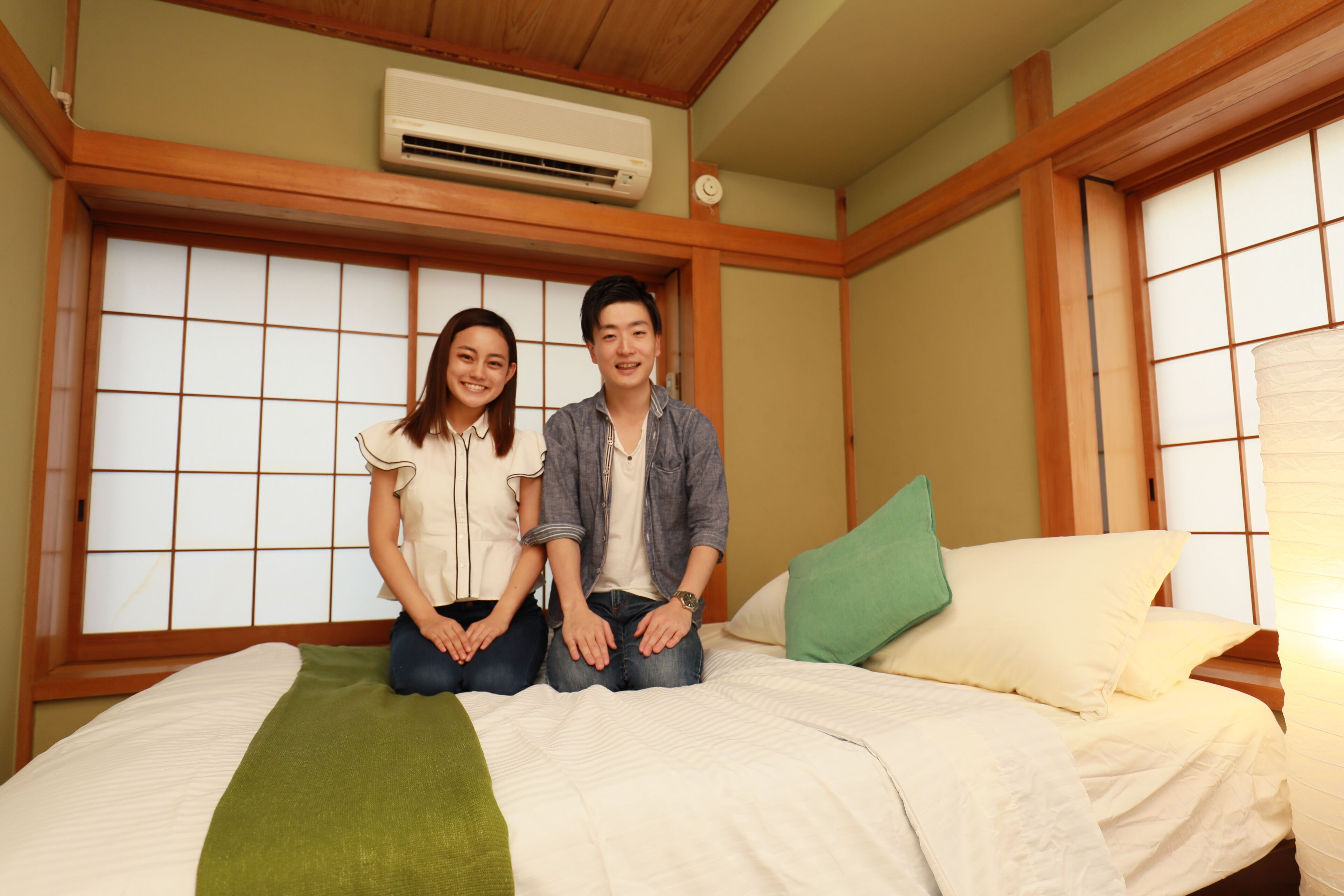 Una habitación con una cama, una ventana con marcos de madera y un equipo de aire acondicionado en la pared.