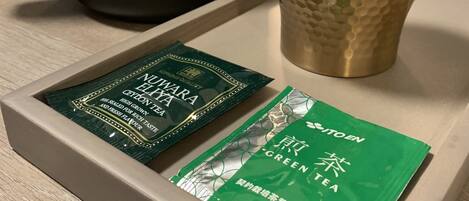 A tray with a black coffee maker, a textured cup, and two green tea packets.