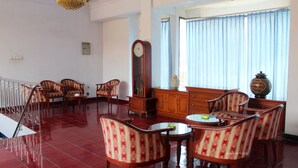 A spacious room with a dining area, a large clock, and a decorative vase. - Wisma Rajawali Cirebon (Cirebon)