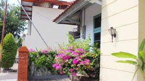 A paved pathway leading to a building with a white exterior and a red brick pillar. - Wisma Rajawali Cirebon (Cirebon)