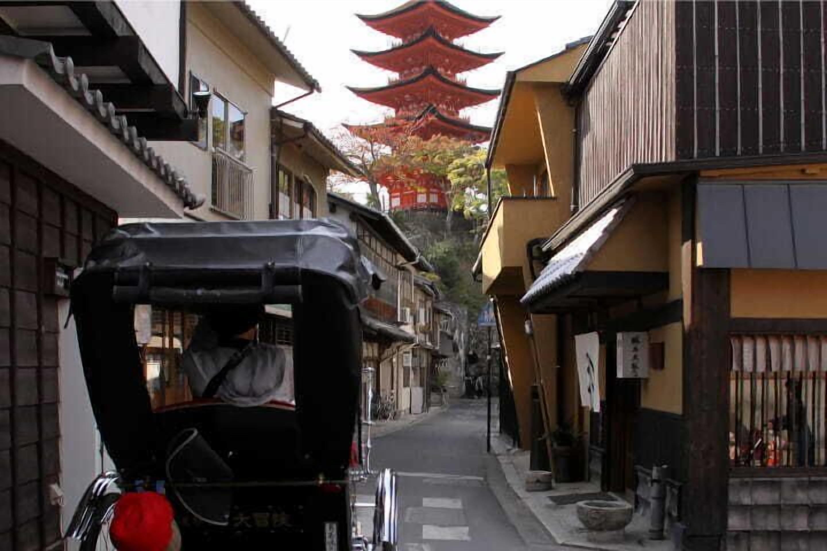 A narrow street with traditional buildings, a covered bicycle, and a pagoda in the background.