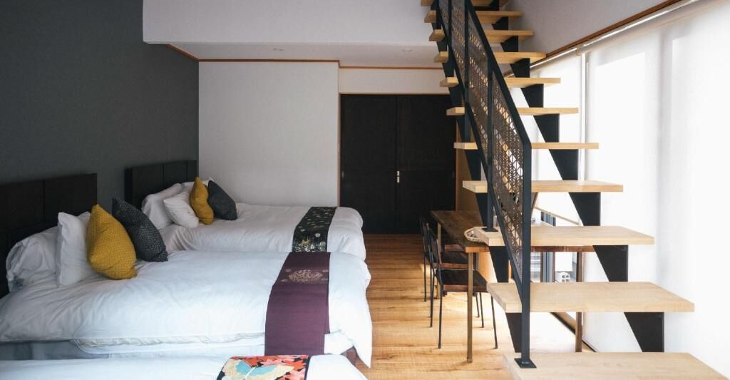 A bedroom with a large bed, a wooden staircase, and a small table.