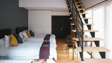 A bedroom with a large bed, a wooden staircase, and a small table.