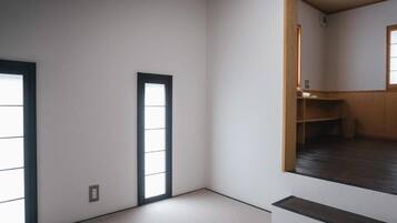 A room with tatami flooring, a sliding door, and a small wooden shelf.