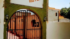 Ein Hotel Eingang mit einem Schild, auf dem 'Calendas HOTEL' steht, über einem schmiedeeisernen Tor.