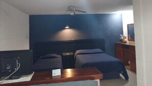 Ein Schlafzimmer mit Bett, Schreibtisch, Stuhl, Computer und Deckenventilator.