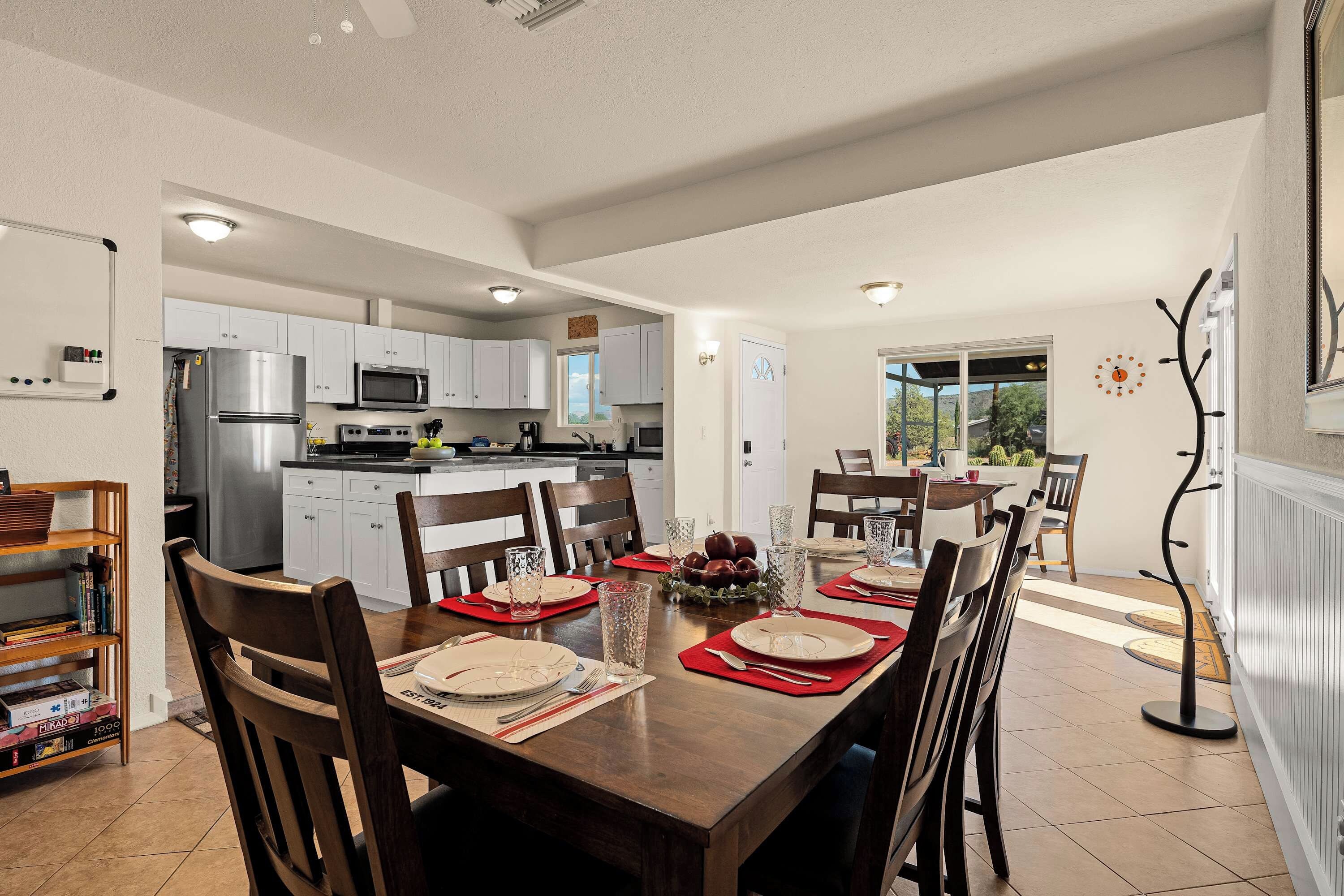 A modern kitchen with white cabinets, stainless steel appliances, and a dining area with a wooden table set for four.