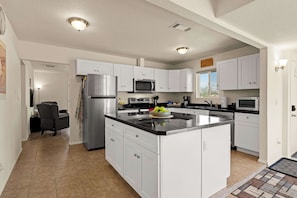 A modern kitchen with white cabinets, stainless steel appliances, and a central island. - Rustic Cottage Feel, Close to Wineries, Sleeps 6! (Cornville)