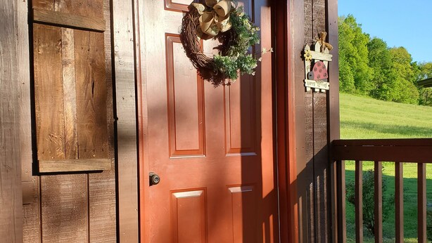 A wooden door with a wreath and a welcome mat. - The BirdDog Farm Cabin #4    (Dixon Springs)
