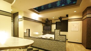 Ein Hotelzimmer mit Wandpaneel in ZEBRA-Muster, einem Bett mit weißen Leinentextilien, einem Flachbildfernseher und einer Decke mit Sternenmuster.