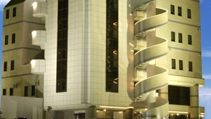 Ein modernes Hotel mit einem gut sichtbaren 'HOTEL'-Schild, einer zentralen Spiraltreppe und einer Fassade im Rasterdesign.