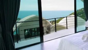 Una habitación de hotel con un amplio ventanal que ofrece vistas al océano y un edificio moderno.