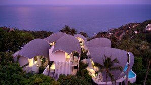 Un resort moderno con varias edificaciones conectadas, una piscina y vista al océano.