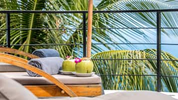 Relax in a serene outdoor setting with a lounge chair and cushioned bench amidst lush greenery.
