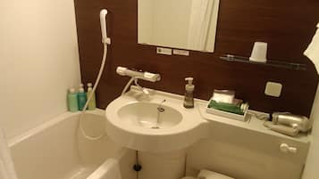 A bathroom with a white sink, a handheld showerhead, a mirror, and toiletries on the countertop.
