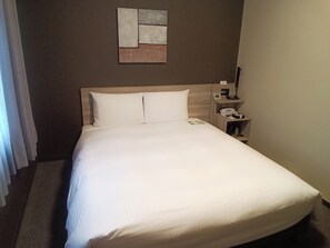 A hotel room with a bed, a nightstand, a lamp, and a wall-mounted artwork. - Hotel Route Inn Hamada Ekimae (Hamada)