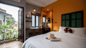 A hotel room with a bed, a desk, and a balcony with plants. - Centraltique Hidden Oasis (Hanoi)