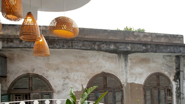 A balcony with wicker pendant lights, a white metal chair, and potted plants. - Centraltique Hidden Oasis (Hanoi)