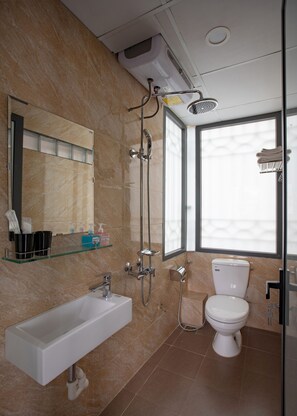 A modern bathroom with a glass shower enclosure, a white sink, and a toilet.