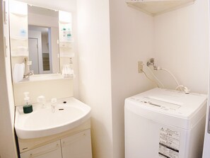 A bathroom with a sink, mirror, and a white washing machine. - OUCHI HOTEL Takeya (Hiroshima)