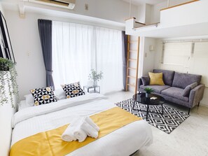 A modern hotel room with a large bed, a sofa, a coffee table, and a view of the outdoors. - OUCHI HOTEL Takeya (Hiroshima)