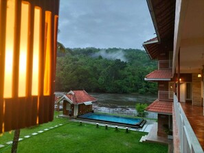 A view of a house with a swimming pool, a small wooden structure, and a river in the background. - Willow Heights Athirapally (Chalakudy)