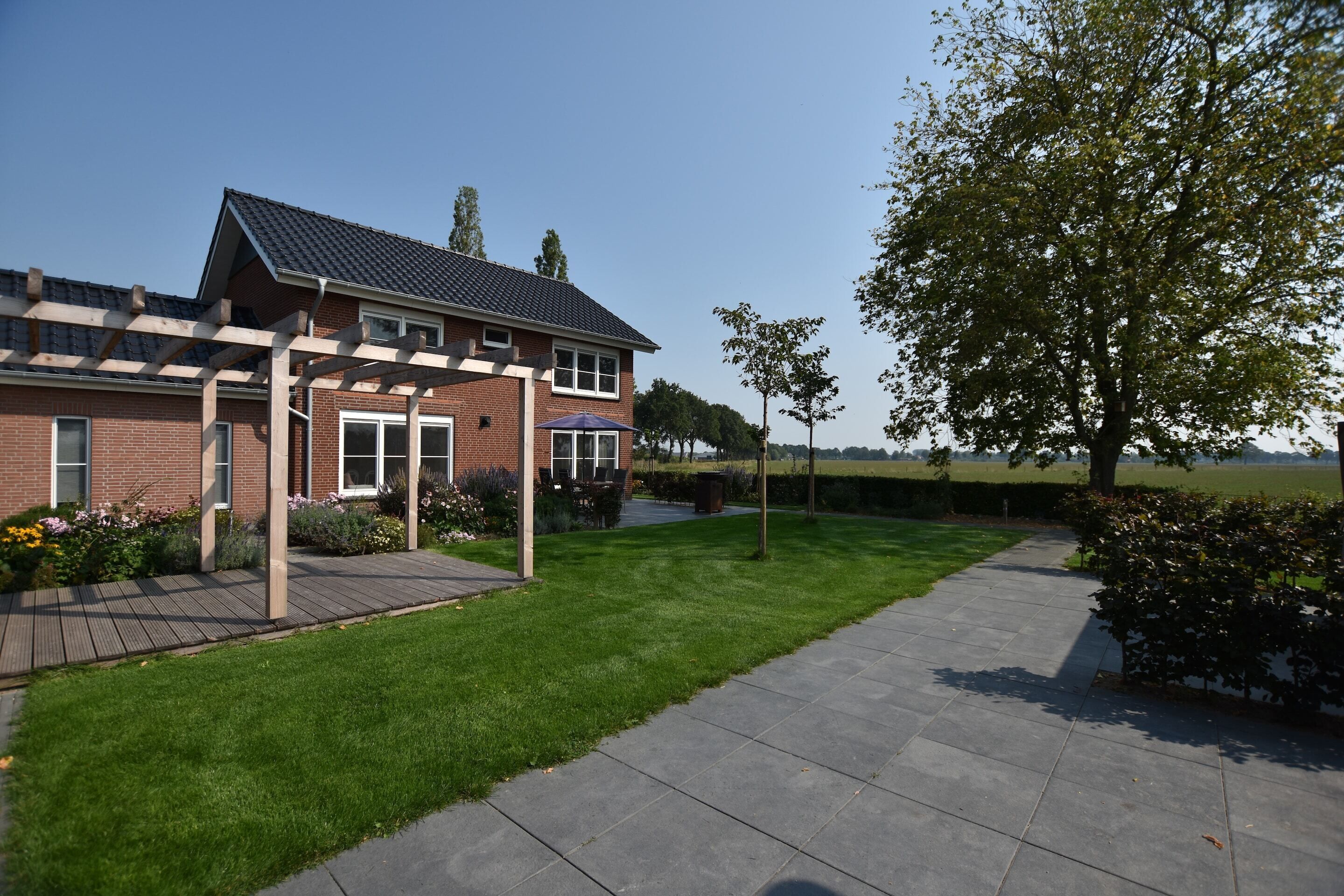 A residential house with a brick exterior, a covered patio, and a well-maintained lawn.
