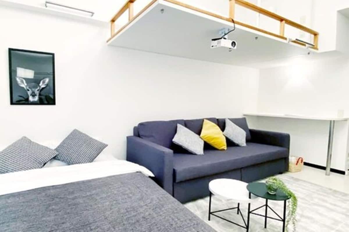 Ein modernes Hotelzimmer mit Bett, Sofa, kleinem Tisch und einer Deckenprojektion.