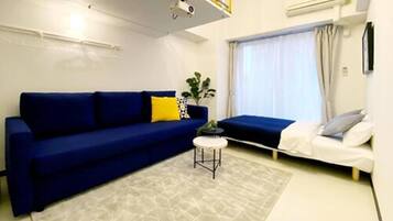 A modern living room with a blue sofa, a small round table, and a window with curtains.